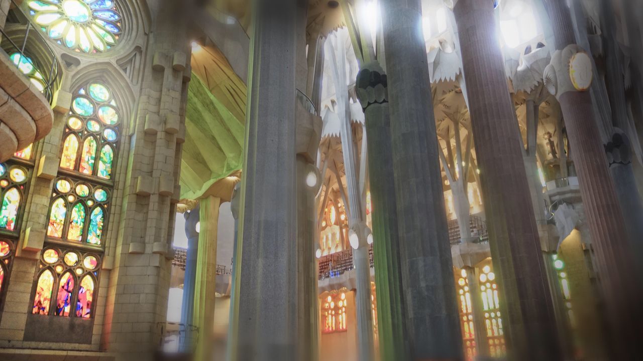 low angle view, window, church, religion, indoors, illuminated, stained glass, glass - material, column, architecture, architectural column, modern, place of worship, architectural feature, electric light, colonnade, green color, city life