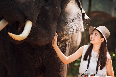 Smiling teenage girl touching elephant