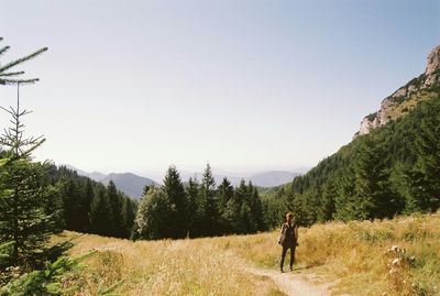 Rear view of woman standing on grassy field against clear sky