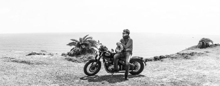 Man riding motorcycle on beach against clear sky