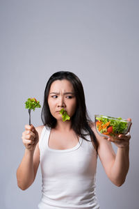 Beautiful young woman holding food against gray background