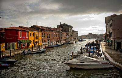 Boats moored at canal amidst houses