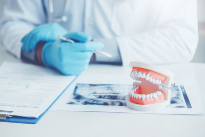 Midsection of dentist sitting denture and medical x-ray in medical clinic