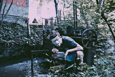 Man sitting by plants in forest