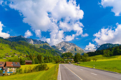 Road amidst trees and mountains against sky