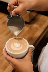 Cropped hand holding coffee on table