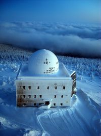 Snow on land by sea against sky