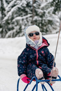 Portrait of young woman sitting on snow