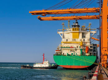 A tugboat pushing a container vessel during berth at an industrial port.