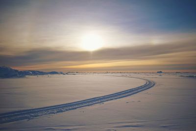 Scenic view of snow covered land against sky during sunset