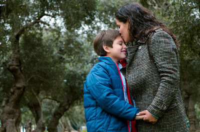 Mother and daughter against trees