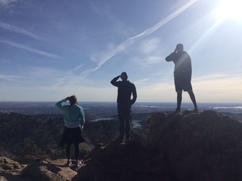 Rear view of friends standing on mountain against sky