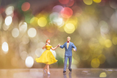 Close-up of dancing figurines on table against lights