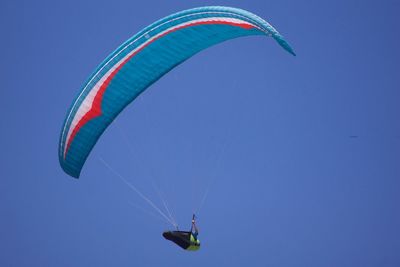 Low angle view of person paragliding against clear blue sky