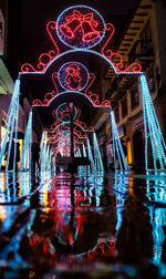 Illuminated building by pond at night