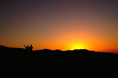 Silhouette man on field against sky during sunset