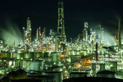 Illuminated factory against sky at night