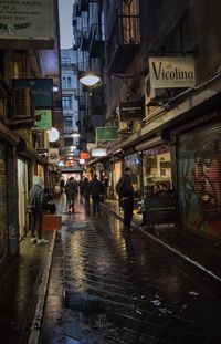 People walking on wet street at night