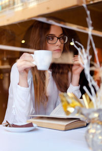 Close-up of teenager holding coffee cup while sitting in restaurant