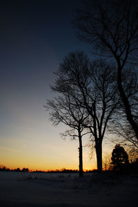 Silhouette bare trees on landscape against clear sky at sunset