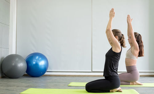 Side view of women doing yoga in gym