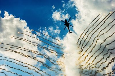 Low angle view of airshow against cloudy sky