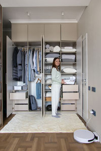 Side view of woman standing by cupboard