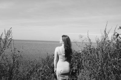 Rear view of woman standing on field against sky