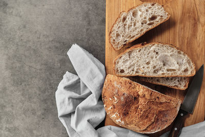 Sliced loaf of artisan sourdough bread on a cutting board on a gray concrete table.