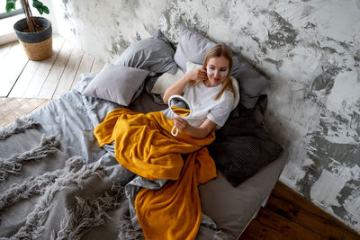 Young woman admires herself in mirror while in bed