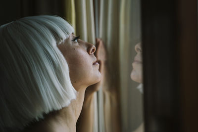 Woman looking up while standing by window at home