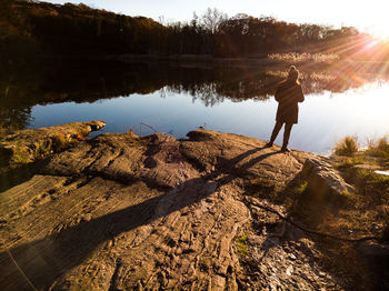 Rear view of man standing by lake against sky