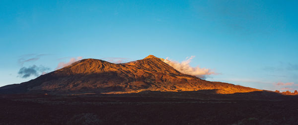 Scenic view of mountains against blue sky