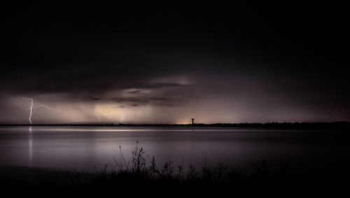 Scenic view of sea against storm clouds at night
