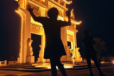 Silhouette people standing at illuminated city at night