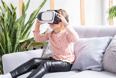 Cute little girl in virtual reality glasses at home. happy kid using vr headset