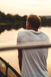 Rear view of man standing by lake