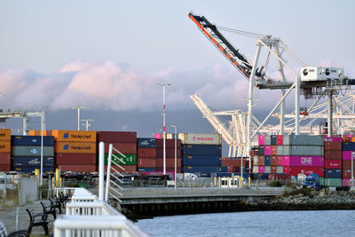 Cranes at harbor against sky