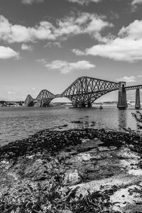 Bridge over river against cloudy sky