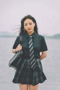 Damsel in uniform by a lake on a cloudy day