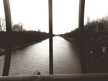 Close-up of railing by river against clear sky