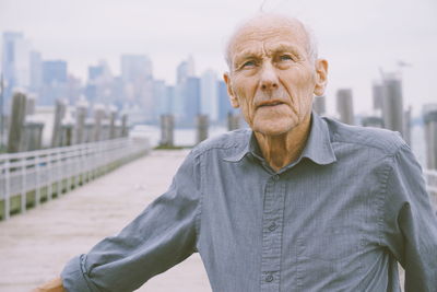 Senior man looking away while standing in city