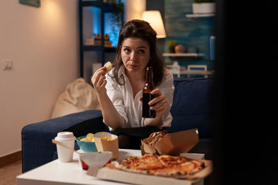 Young woman having food at home