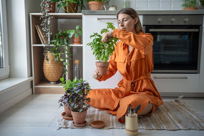 Portrait of young woman holding christmas tree at home