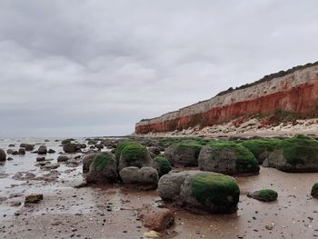 Rock formation on beach against sky