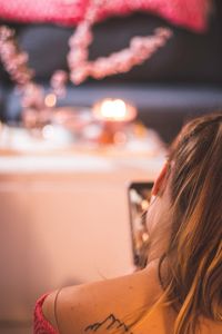 Rear view of woman using phone at home