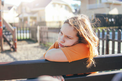 Thoughtful girl sitting on park bench