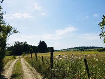 Road amidst field against sky