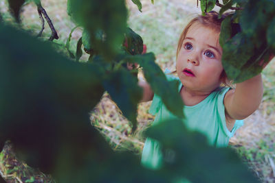 Baby girl standing by tree on land