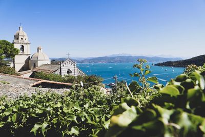 Scenic view of sea by buildings against clear blue sky